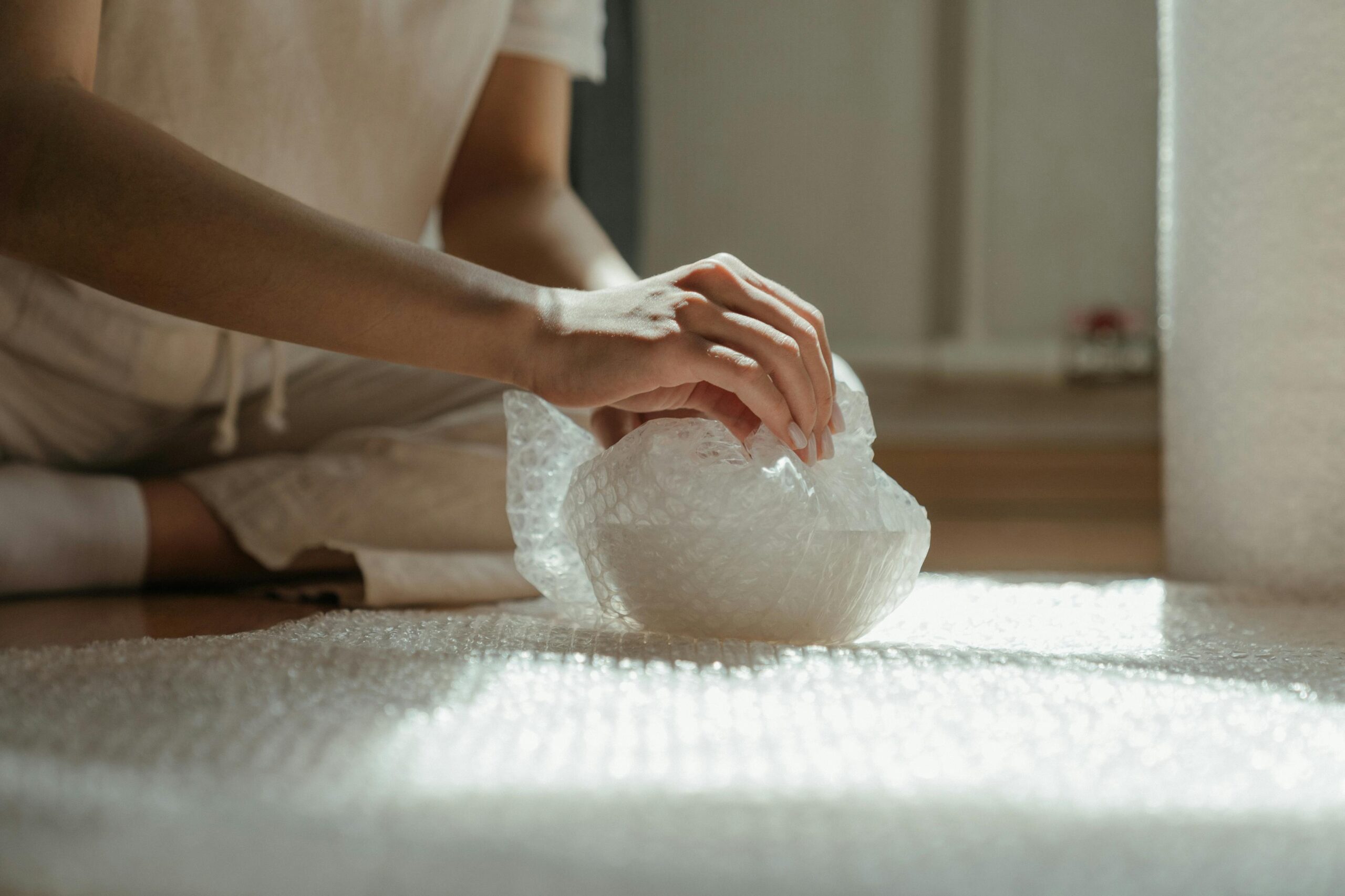 Close-up of hands wrapping an object in bubble wrap for safety during a move.