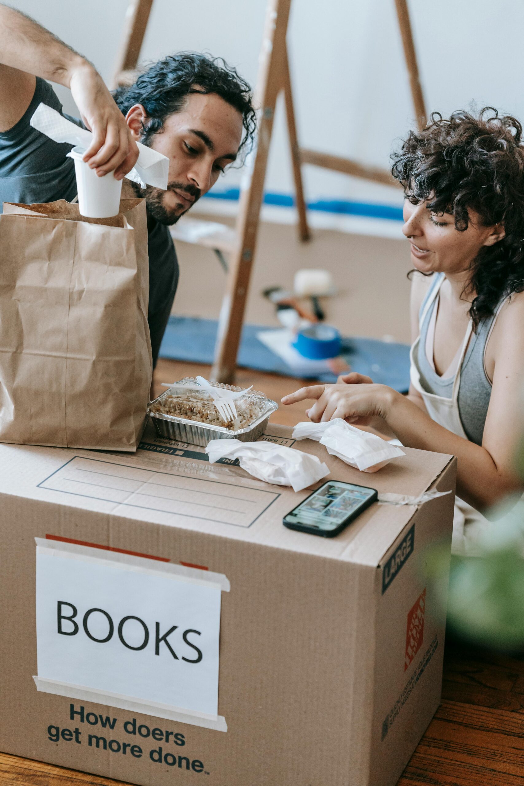 A couple busy packing books and food in their apartment for relocation.